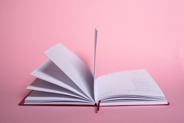 An open notebook for notes lies on a pink background