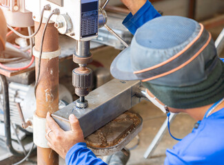 Technician drilling in Steel pipe with Bench Drill.