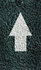 White pointing arrow on a textured asphalt surface.