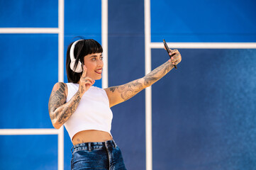 Una mujer caucásica con tatuajes y pelo corto tomandose unas fotos con la cámara del teléfono en una pista deportiva 
