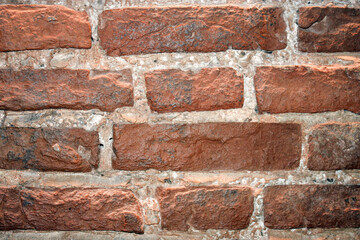 Fragment of old brickwork. Flat lay, close-up. Cracks and defects in the red brick on the wall are illuminated by bright light. Potholes and defects in red brick.