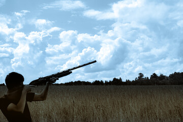 Young man hunter silhouette takes aim at a distant target blue sky yellow field