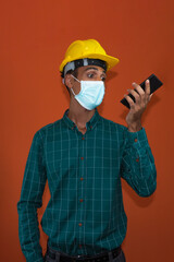 Fototapeta na wymiar Engineer, architect or worker with yellow helmet and pandemic mask isolated on white background. Engeneer at work talking on the cell phone.