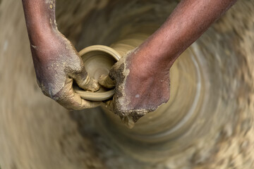 A male potter's hands preparing a clay pot on a potter's wheel. Close-up. Selective focus.