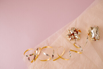 Decorative gift golden bow with ribbons, on a pink background. Gift wrapping for the holiday.