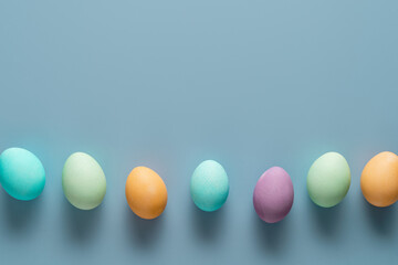 Easter holiday concept. Easter picture, multi-colored eggs, spring flowers on a light blue background. Happy Easter
