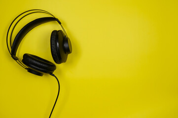 Black headphones on a yellow background. Top view.Copy space