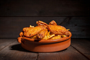 Grilled chicken wings on a rustic plate on wooden table. High quality photography