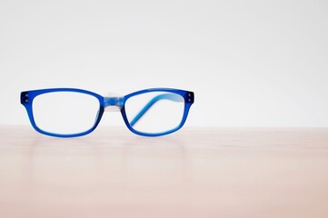 paio di occhiali da vista in plastica blu riparati con nastro adesivo appoggiati su una superficie...