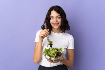 Teenager Ukrainian girl isolated on purple background holding a bowl of salad with happy expression