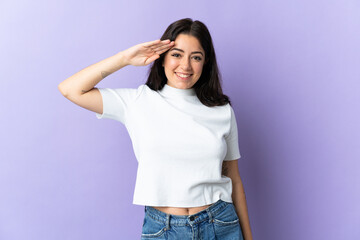 Young caucasian woman isolated on purple background saluting with hand with happy expression
