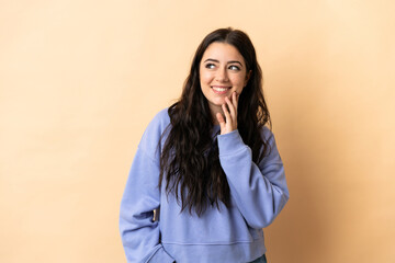 Young caucasian woman over isolated background looking up while smiling