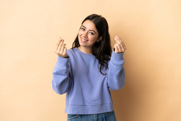 Young caucasian woman over isolated background making money gesture