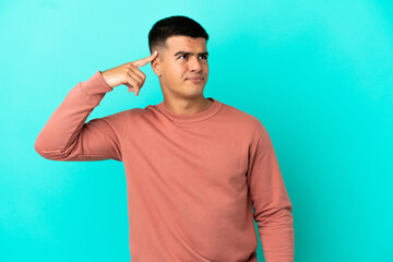 Young handsome man over isolated blue background making the gesture of madness putting finger on...