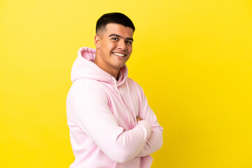 Young handsome man over isolated yellow background looking to the side and smiling