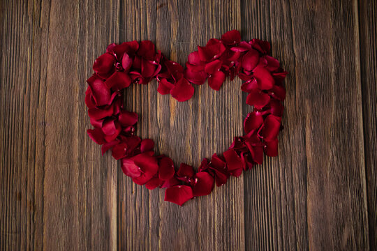 beautiful photo of a heart made of red rose petals in the center on  wooden floor, surprise for valentine's day, date, love