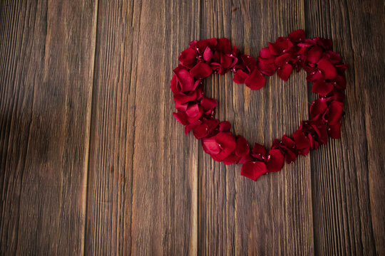 beautiful photo of a heart made of red rose petals on  wooden floor, surprise for valentine's day, date, love