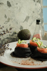 Fried pancakes with salmon.
Black food with cuttlefish ink. Delicious and satisfying pancakes for Shrovetide. Homemade food, lunch, dinner. Concept: pancake week holiday food. Maslenitsa