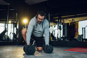 Middle aged men training in the gym and using dumbbells