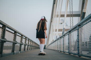 Young woman riding her longboard on the bridge