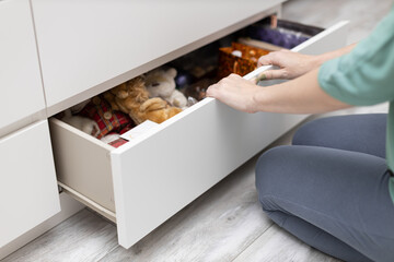 woman sitting in front of an open bottom drawer of a chest of drawers