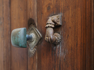 Wooden door, handle and door knocker in the shape of a woman's hand.
