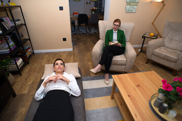 Young woman patient on psychotherapy lying on the couch and talking to her psychiatrist