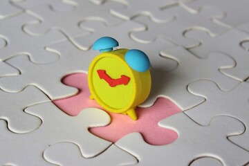 Missing jigsaw puzzle pieces and alarm clock. Time management concept.