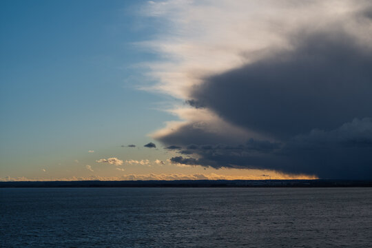 A dramatic image of a rain cloud on the horizon above the sea and a peninsula