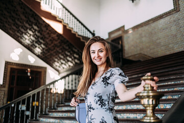 Cheerful carefree Caucasian woman descending some stairs of a Palace sightseeing in Europe