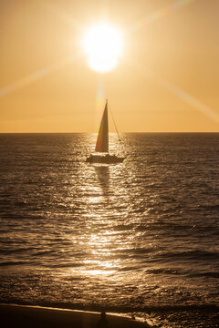Silhouette eines Segelboots im Sonnenuntergang fotografiert mit einem Sternfilter, Sonnenstrahlen