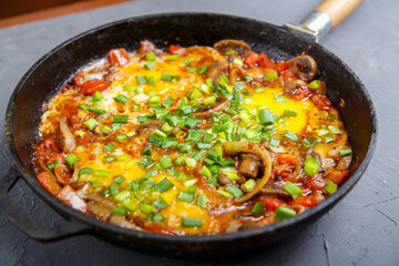 Shakshuka hot with herbs in a frying pan on a gray table.