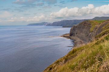 Fototapeta na wymiar Kimmeridge Ledges in the foreground and looking towards Kimmeridge Bay and Gad Cliff of Worbarrow, on the Dorset stretch of the south west coast path