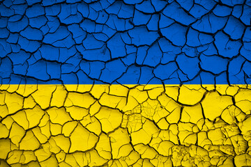 Ukraine national blue and yellow flag on a mud texture of dry cracks on the ground