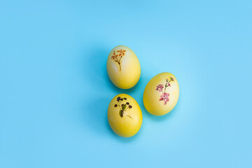Yellow with a plant pattern of eggs lie on a bright blue background. Painted eggs for Easter