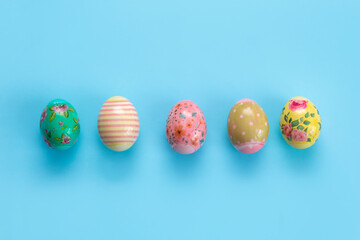 Colorful, painted for Easter, chicken eggs lie in a row on a blue background