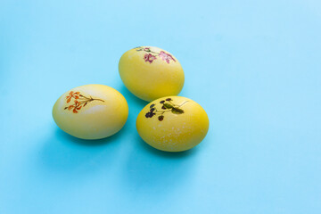 Yellow with a plant pattern of eggs lie on a bright blue background. Painted eggs for Easter