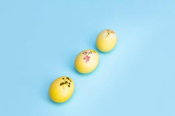 Bright yellow chicken Easter eggs lie in a row on a blue background. An opening to the Easter holiday