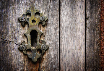 Keyhole in an old rustic panelled wooden door processed for impact