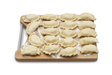Raw pierogi stuffed with white cheese lying on wooden kitchen board on white isolated background....