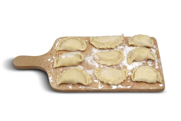Raw pierogi stuffed with white cheese lying on wooden kitchen board on white isolated background. Traditional Polish dish.
