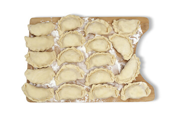 Raw pierogi stuffed with white cheese lying on wooden kitchen board on white isolated background. Traditional Polish dish.