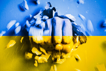 A fist punches through a concrete wall with the colors of the Ukrainian national flag. The concept...