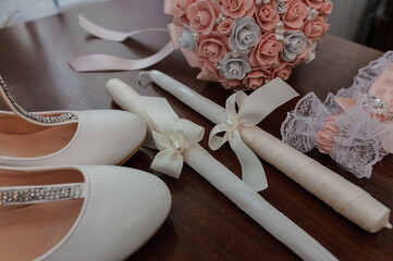 Obraz na płótnie Canvas Bride's accessories. Women's shoes leather, garter, bridal bouquet, candles, pendant