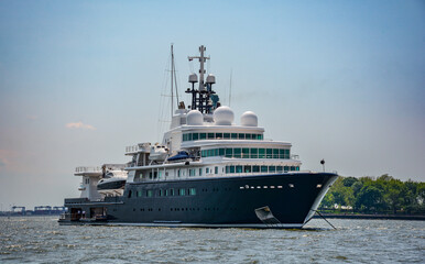 Fototapeta na wymiar Superyacht in New York Harbor with Statue of Liberty in the background