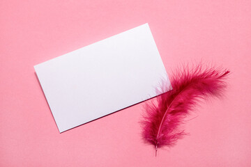 Blank card and vintage mail envelope on pink background with pink feather, top view, copy space. Love letter, romantic message. Card for Mother day, birthday, valentines day