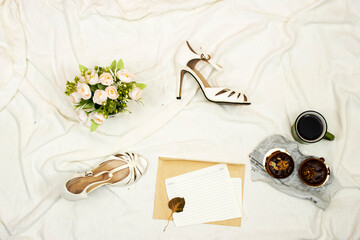 flat lay bed, white shoes and bouquet of flowers, macarons cookies and cup of coffee with copy space. wedding concept