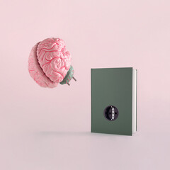 Minimal abstract scene with brain and dark green book with socket, on isolated pastel pink-beige background with copy space. Concept of school, reading or education. The idea of book as brain charger.