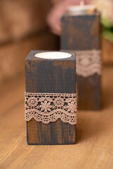 Candles in a wooden stand on a brick wall background