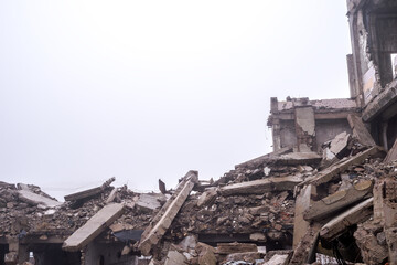 A pile of large concrete fragments of a large destroyed building in a foggy haze. Background
